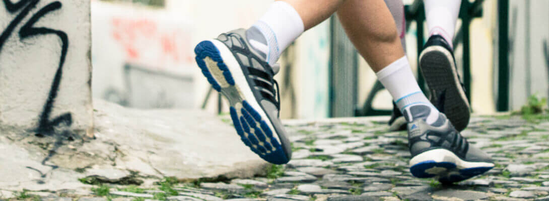 Runner with running socks jogges through the city - focus on the feet with product