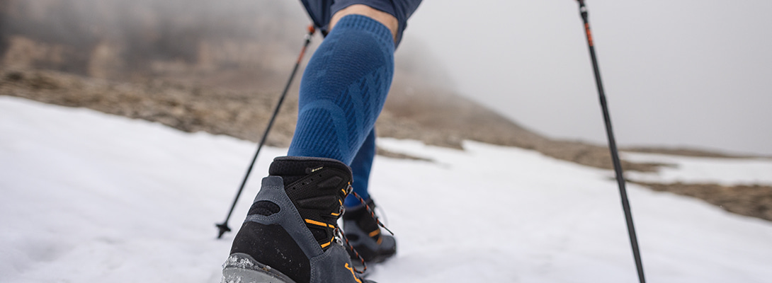 Person hikes via snow covered rocks she wears merino hiking socks