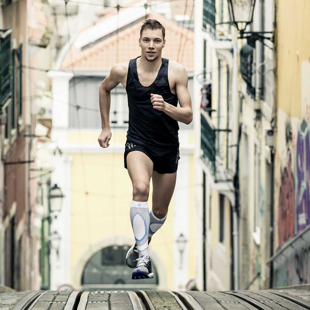 Runner Marcel Bräutigam runs up an increase with tram rails and wears white-blue compression socks