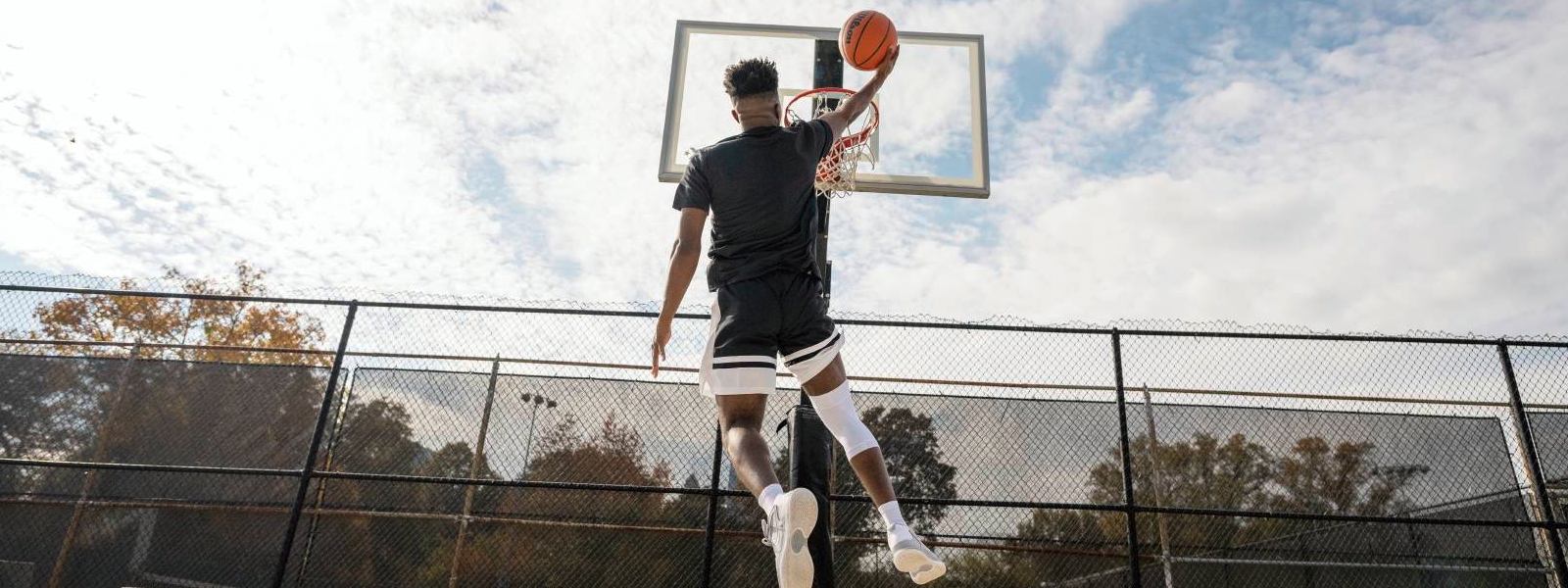 Basketball player jumps on a free space to the basket and is wearing a white knee band