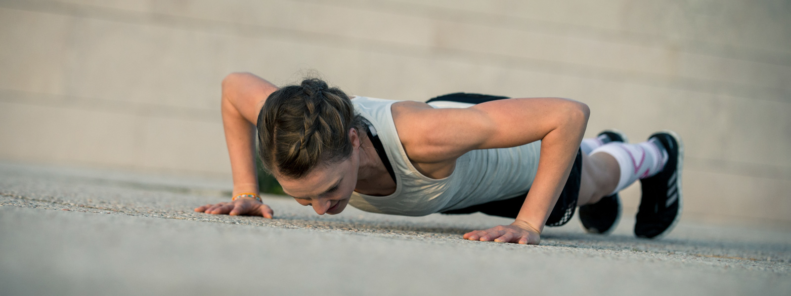Woman puts push-ups on a concrete floor view of diagonal