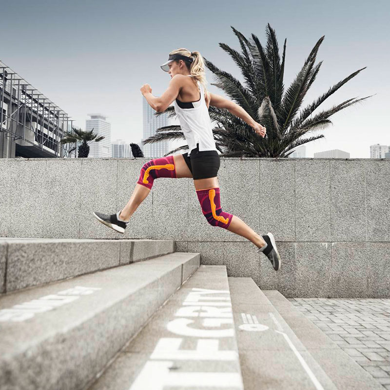 The runner jumps over stairs in the city with a knee band