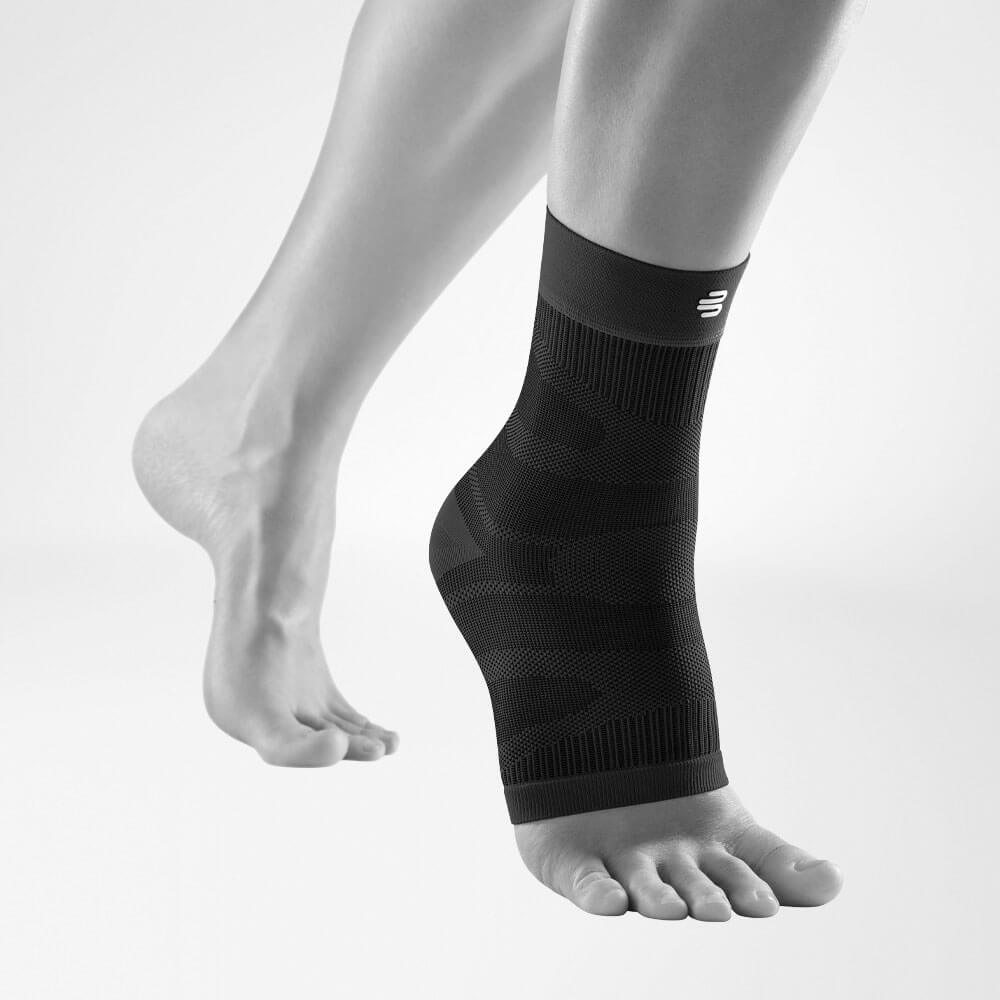 Complete view of the black compression ankle support on a stylized gray leg