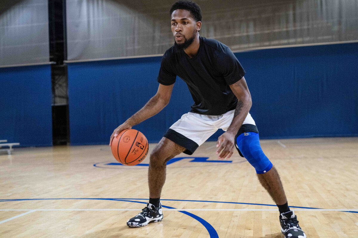 Basketballer dribbles and wears the NBA Knee Sleeve Golden State Warriors