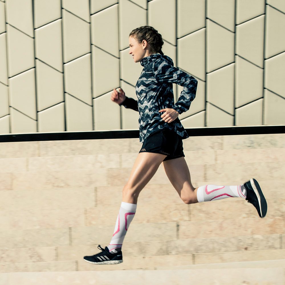 Langer with white-pink running socks runs next to a modern wall