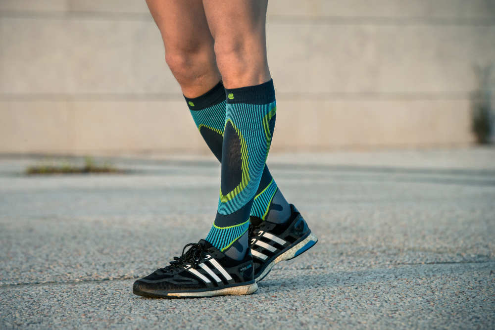 Lower leg of a runner in close -up with blue patterned running socks on a concrete surface