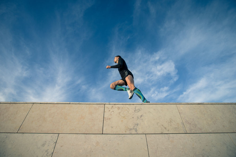 Strong frog perspective: View of a wall on which a man with colorful compression stockings runs