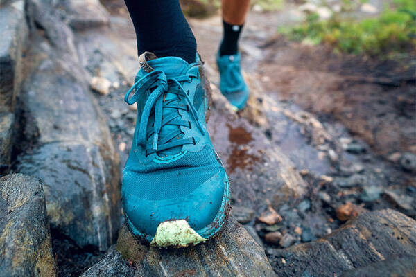 Close up of a blue running shoe on a wet rocky lead