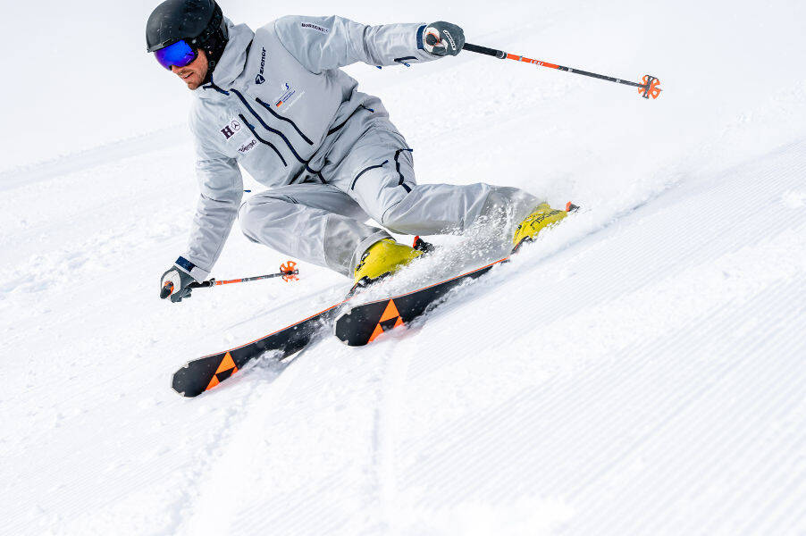 Skiers in a gray suit with a light inclined position in front of him can be recognized by the groove pattern of the stagnated slopes