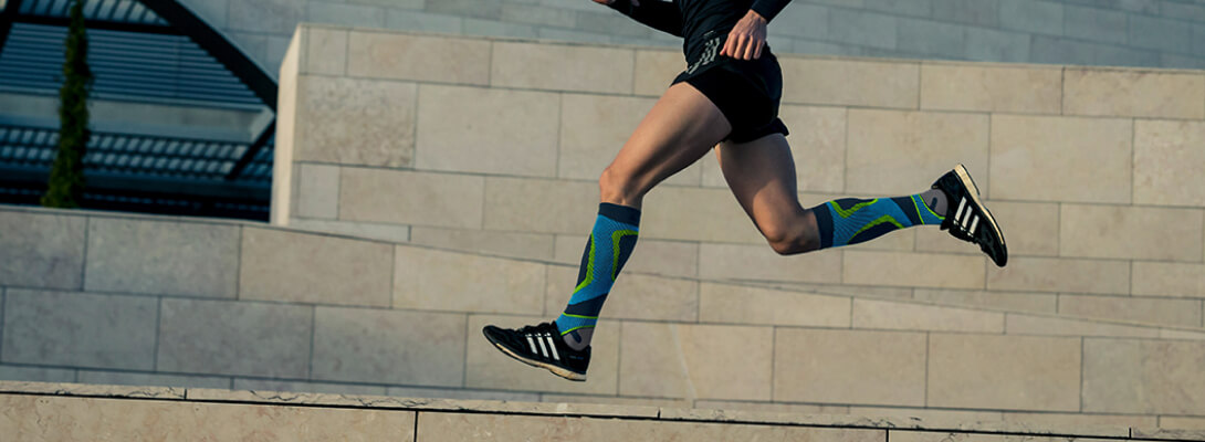 Runner with compression socks to run in front of a stone wall