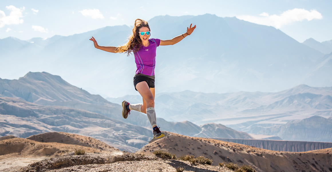 Woman with Wadensleeves makes jumping and is happy about mountain range