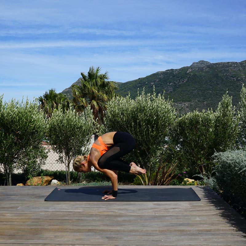Woman makes yoga balanced on her terrace on her hands while her legs hang behind the upper body in the air
