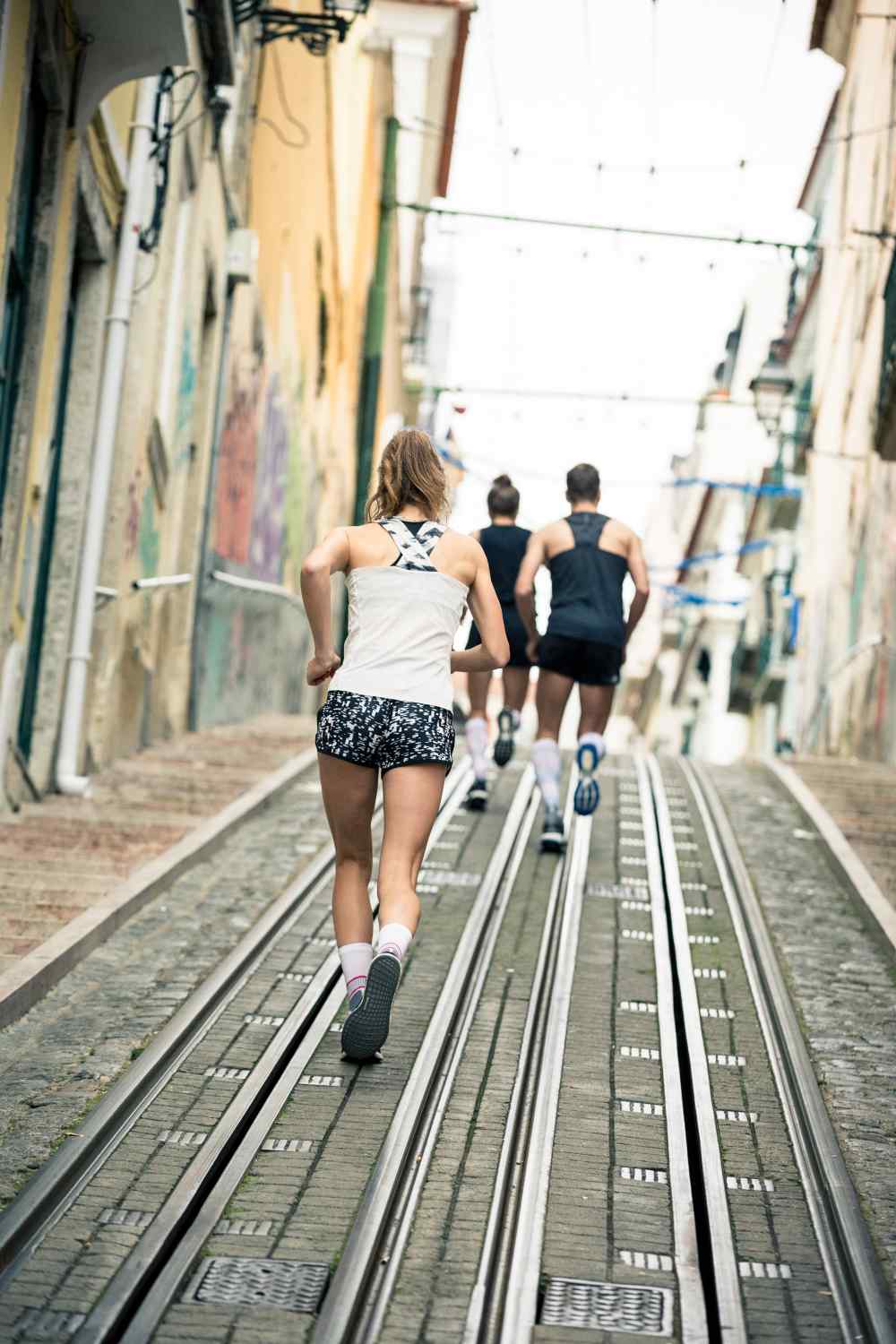 Two runners and a runner run a tram line in a city