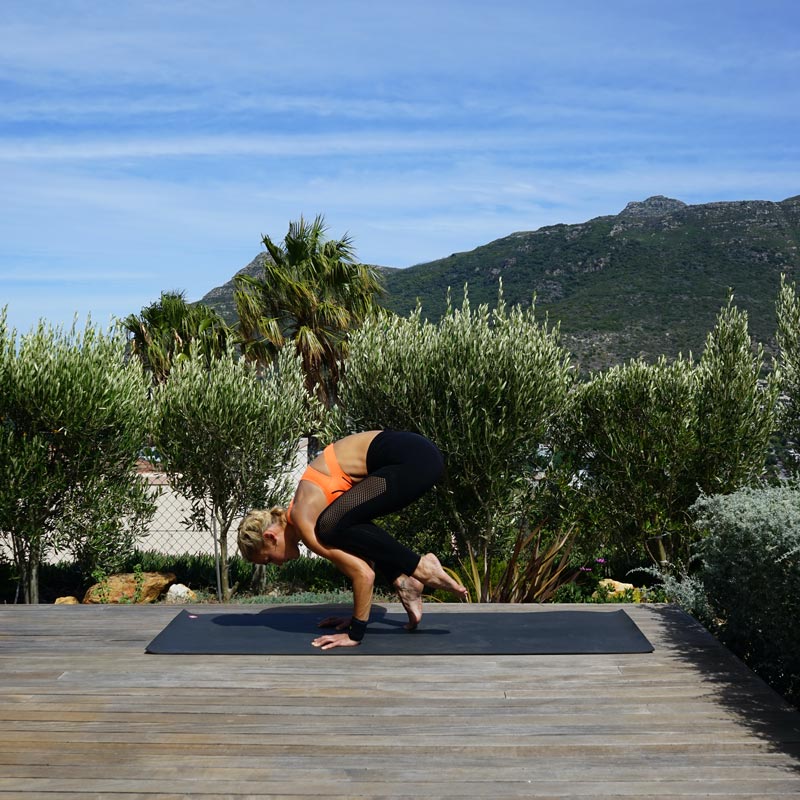 Woman makes yoga balanced on her terrace on her hands while her legs slowly lift herself into the air