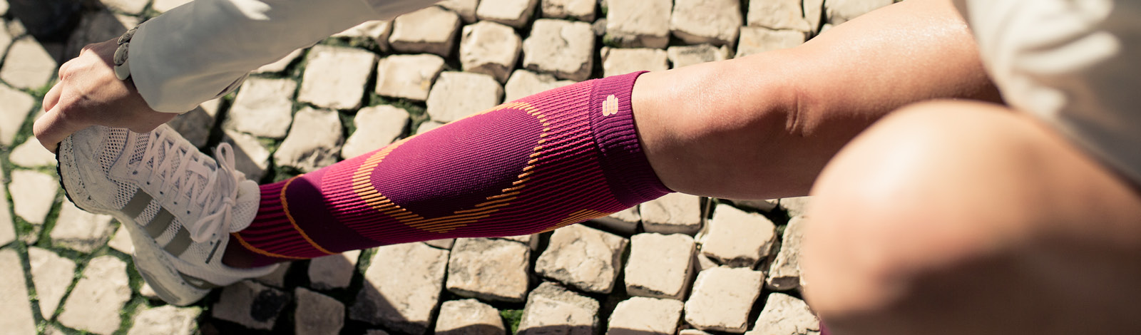 The runner stretches her calf with long running socks in pink