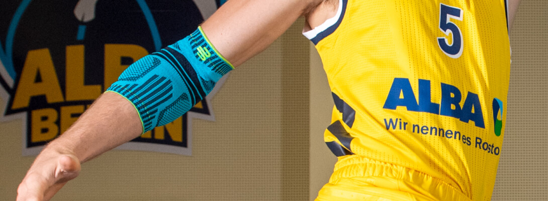 Basketball player with Alba Berlin jersey wears a sports bandage for the elbow
