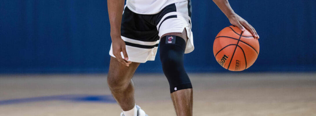 Detailed picture basketball player with a basketball in hand wears a black NBA Knee Sleeve