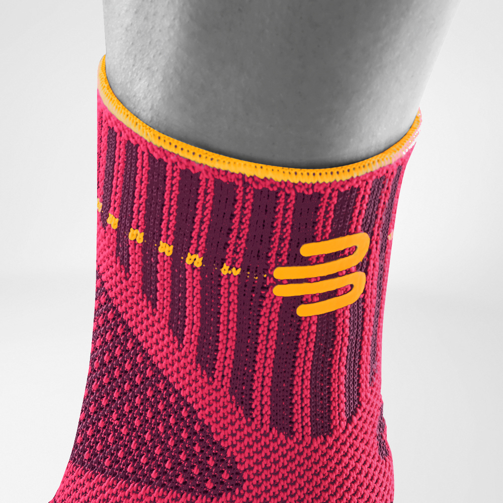 Detailed view of the upper area of ​​the pink sports bandage for the ankle including a knitting course and logo