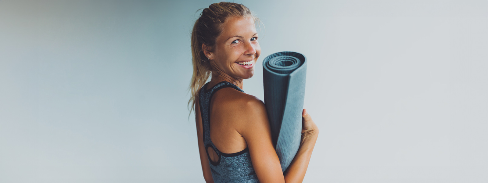 Smiling woman with a yoga mat