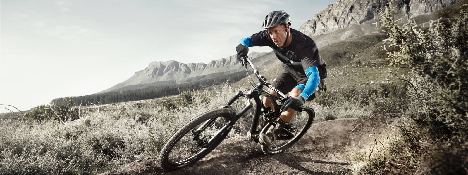 Mountain biker drives down a slope and wears blue arm sleeves