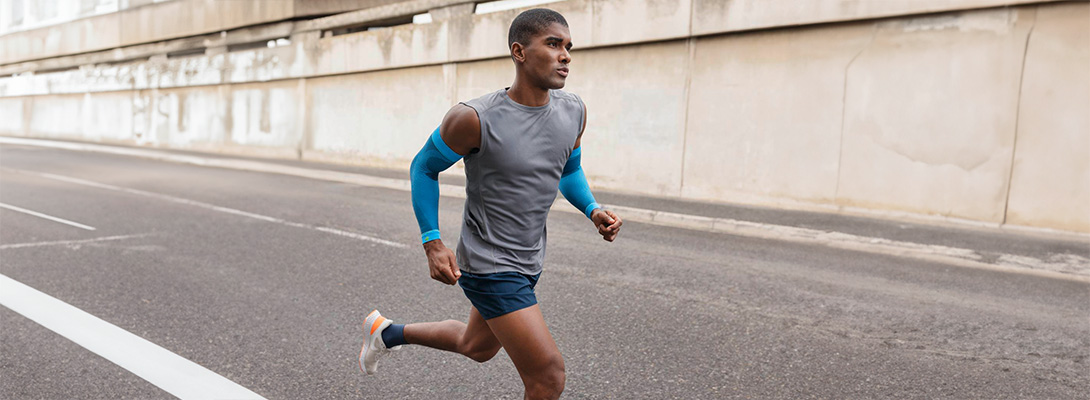 Runner with blue arm sleeves runs through the city on a street