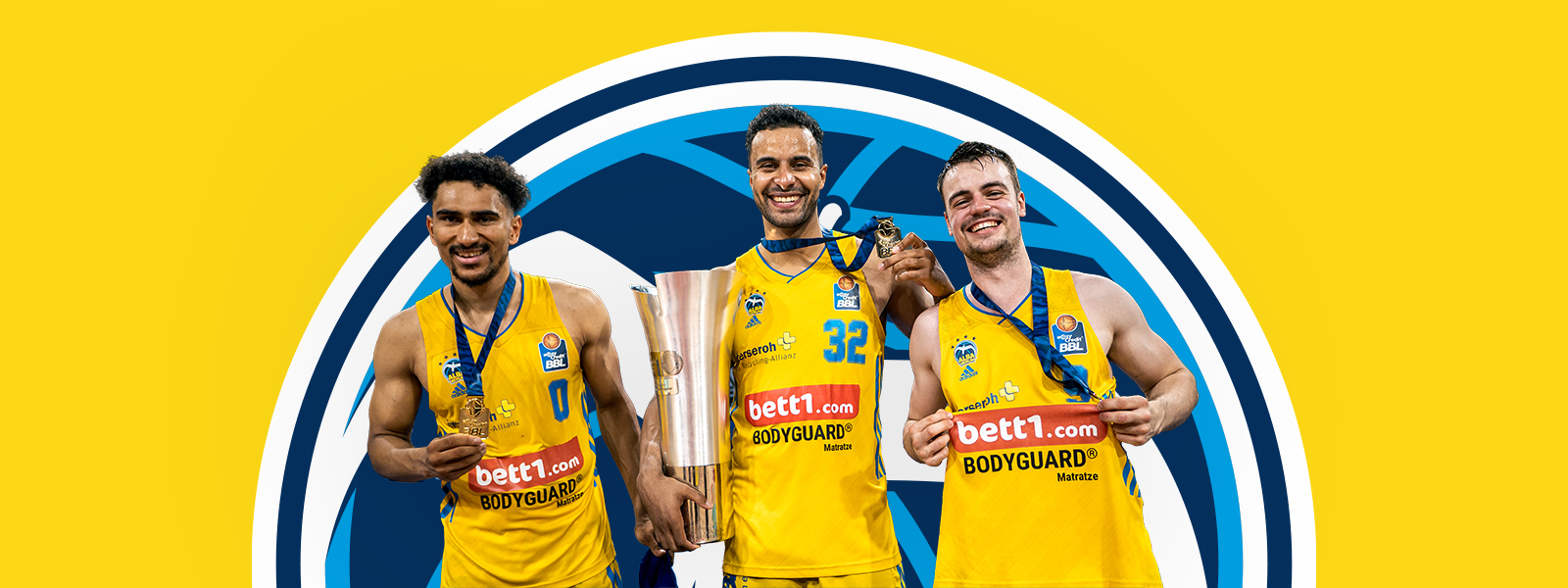 Three players from Alba Berlin with a trophy in front of a yellow area with the Alba Berlin logo