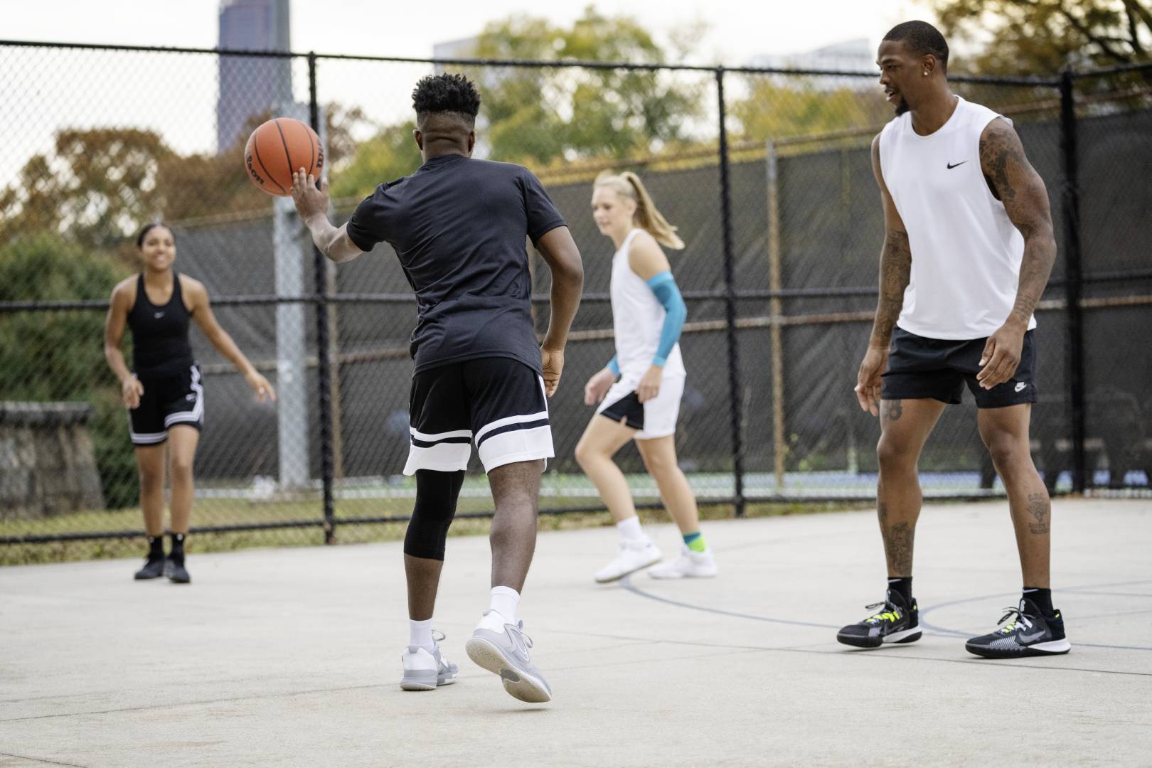 Four players during a street ball game of the players in black game clothes fits the ball with his teammate