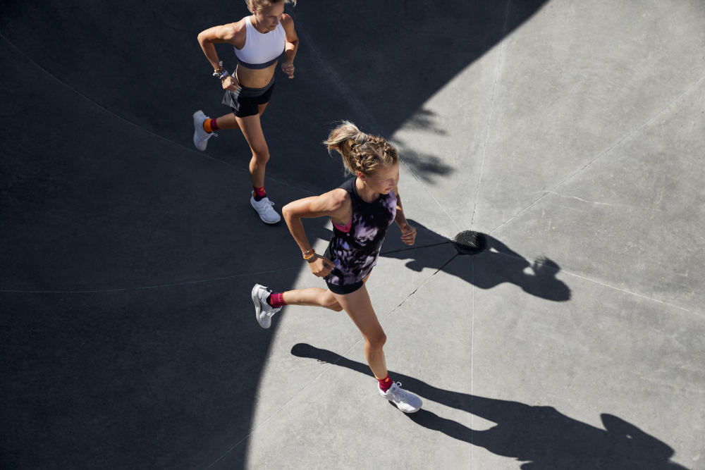 Runners with ankle bandages run in a summer outfit over a concrete surface perspective of diagonally top