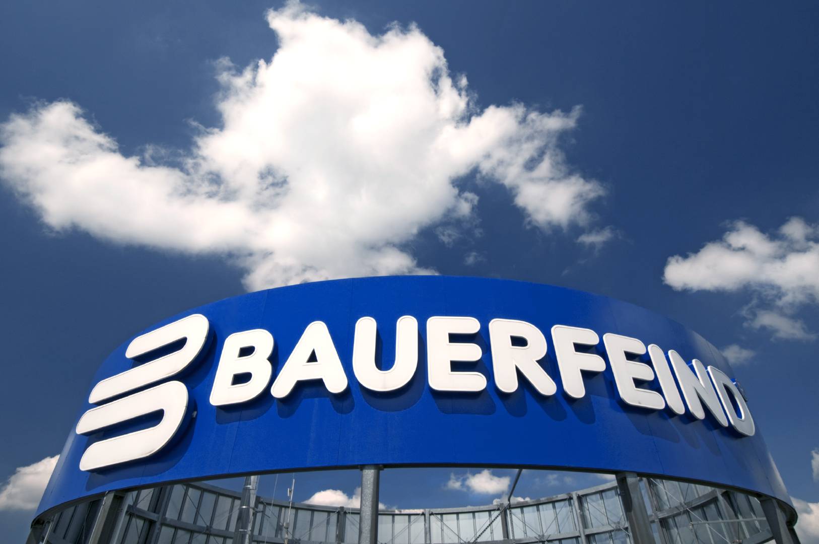 Bauer enemy lettering on a blue surface on the roof of a high -rise building above it blue sky with a cloud