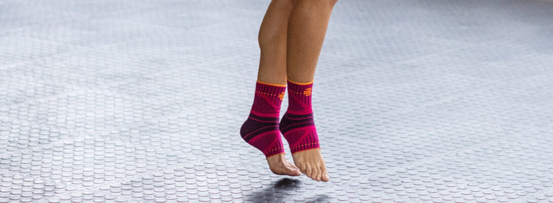 Zoom on a woman's legs The sports bandages for the ankle wears on the tips of the toe on a gray surface