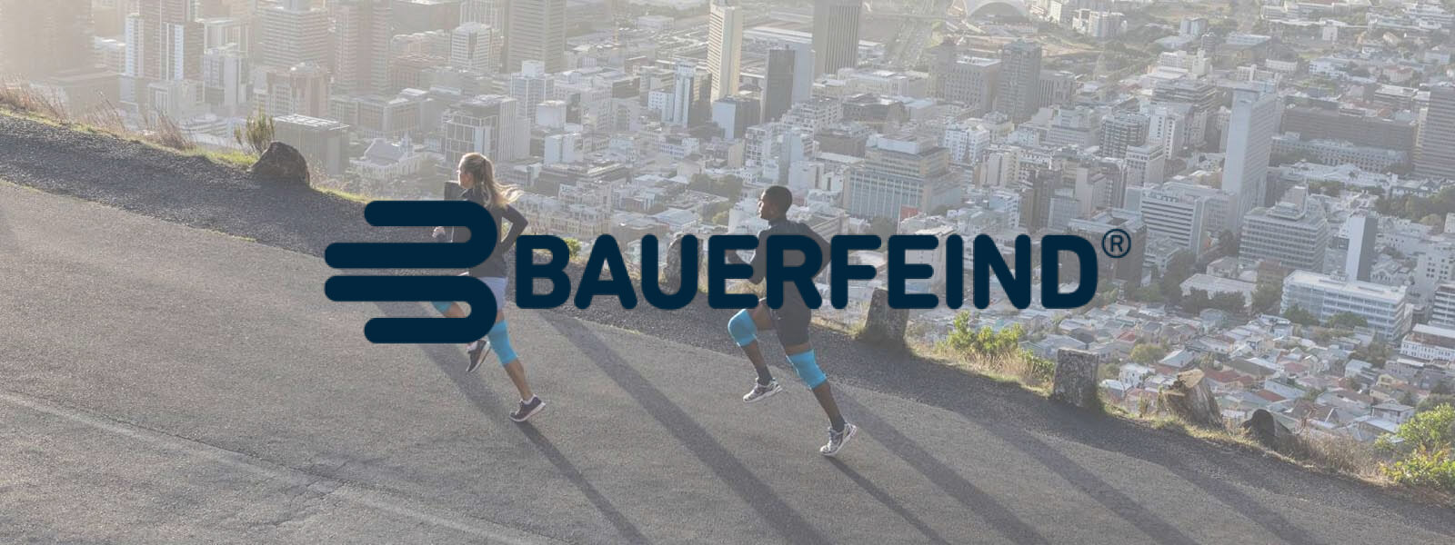 Bauer enemy lettering in a picture where two runners run on a mountain over the city