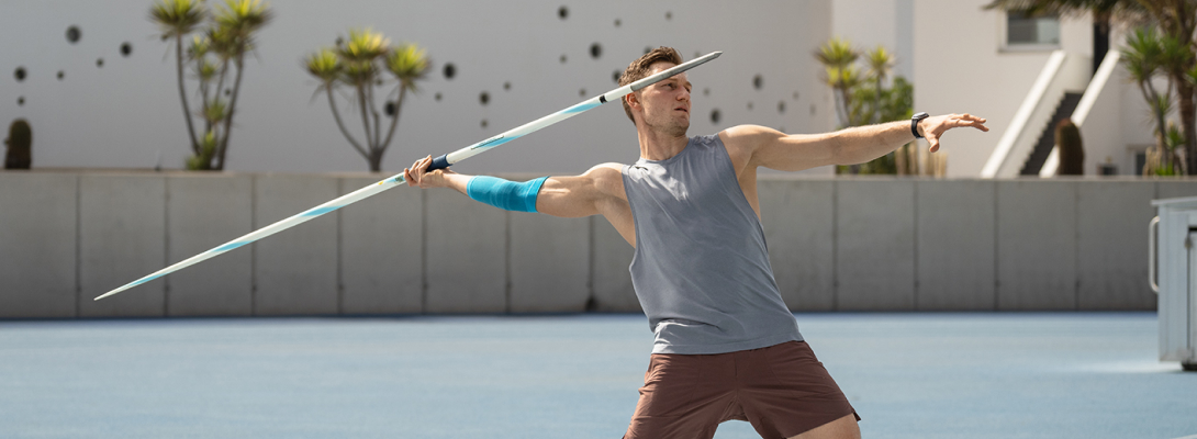 Man trains javelin throw and wears a sports leeve for the elbow