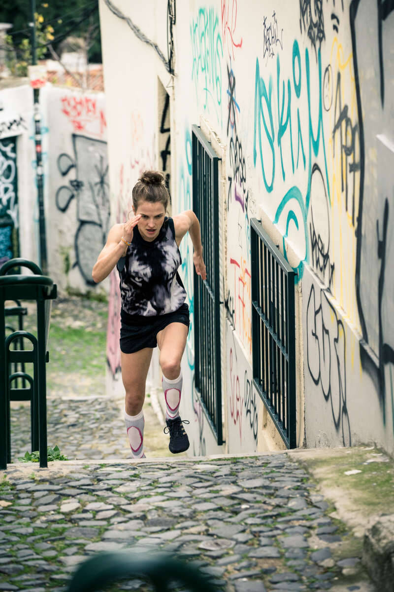 The runner runs a staircase in an old town with numerous graffiti on the walls