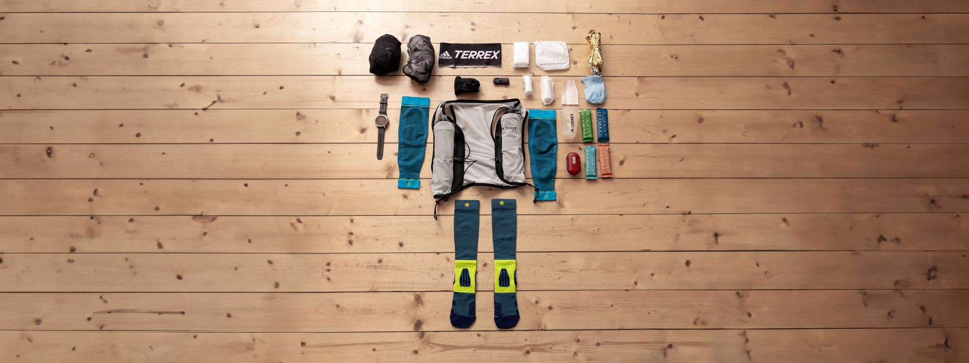Necessary trail run equipment is flat on a wooden floor.