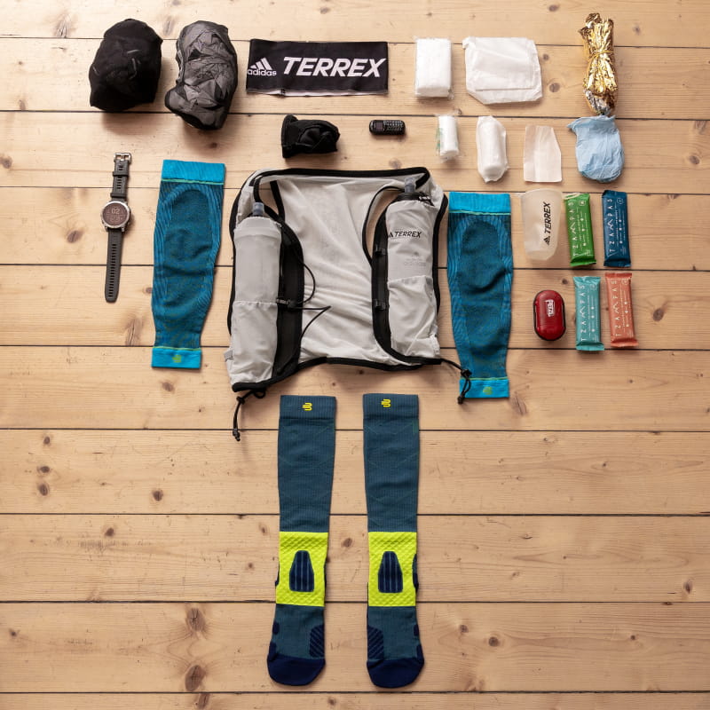 Necessary trail run equipment is flat on a wooden floor.