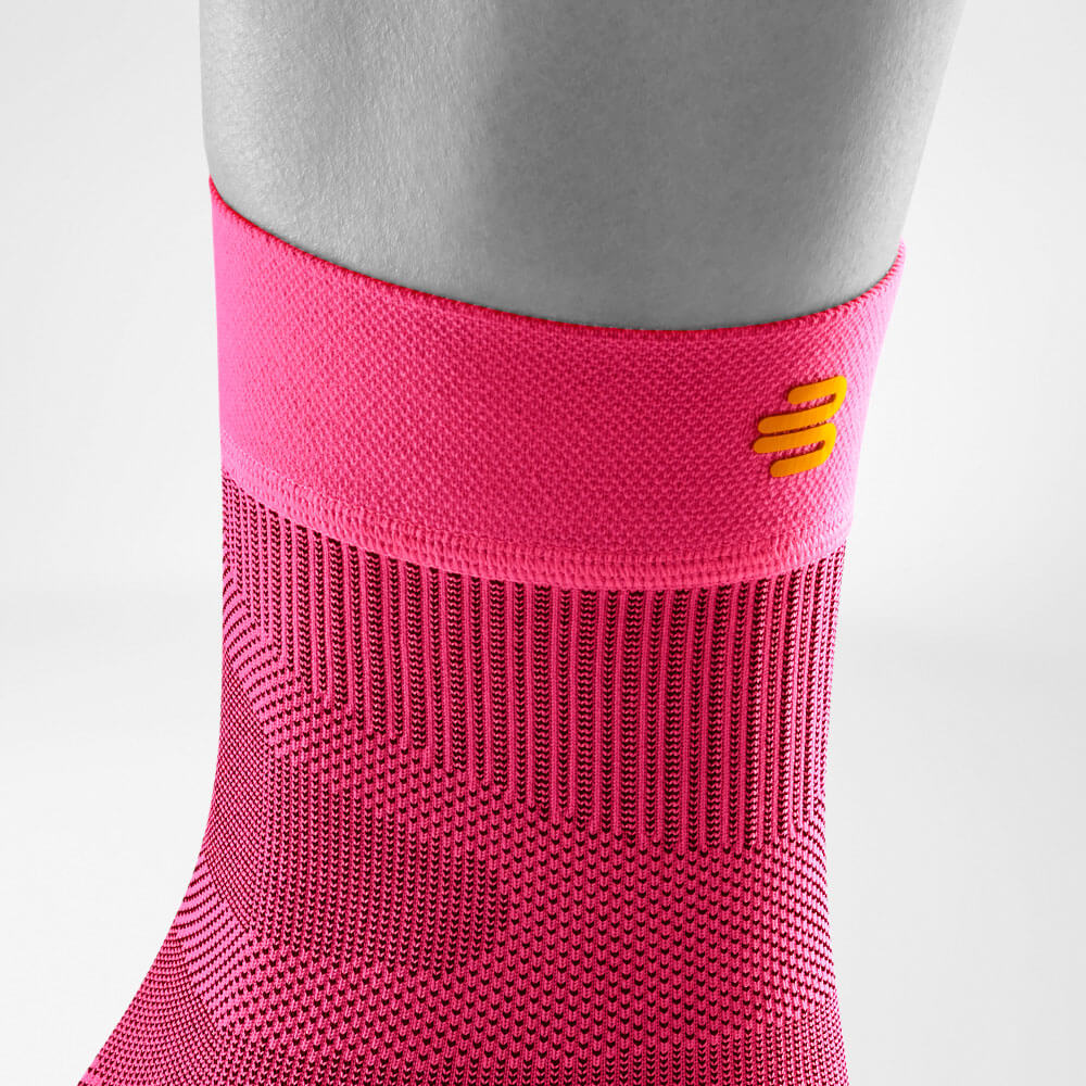 Detailed view of the upper area of ​​the pink-colored Sportsleeves for the ankle including a knitting course and logo