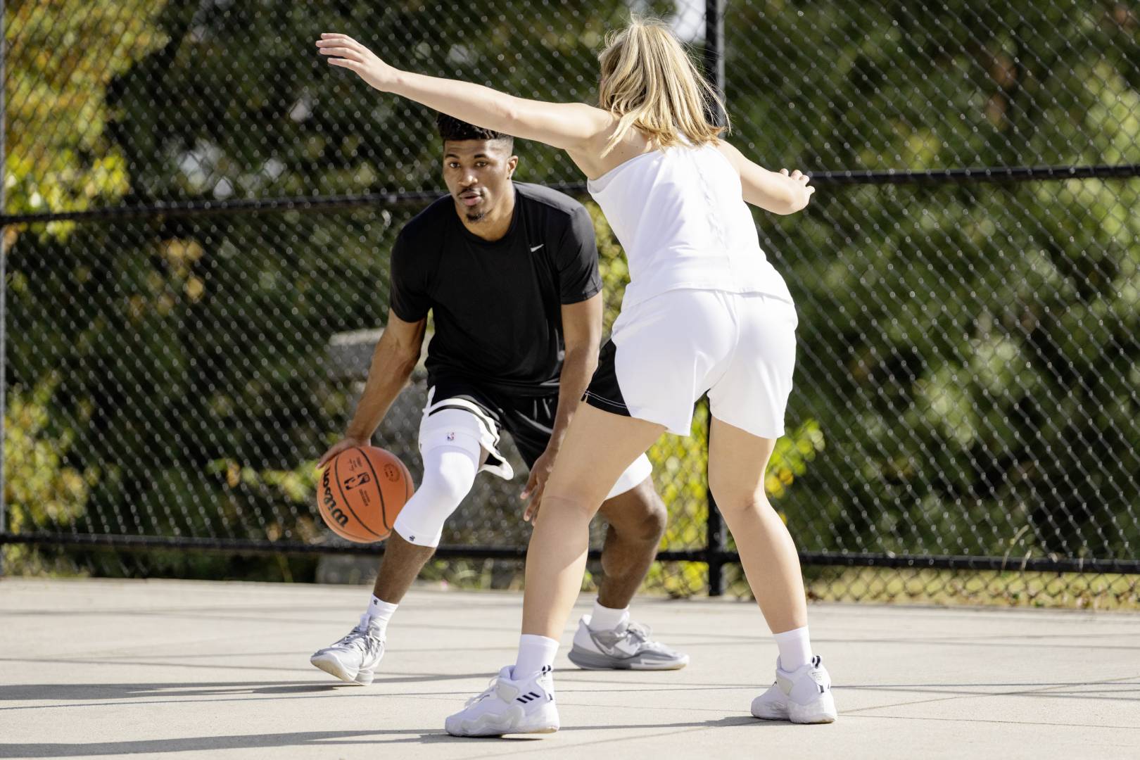 Streetball player with white Knee Sleeve tries to come past an opponent who is waiting for him with the arms spread out