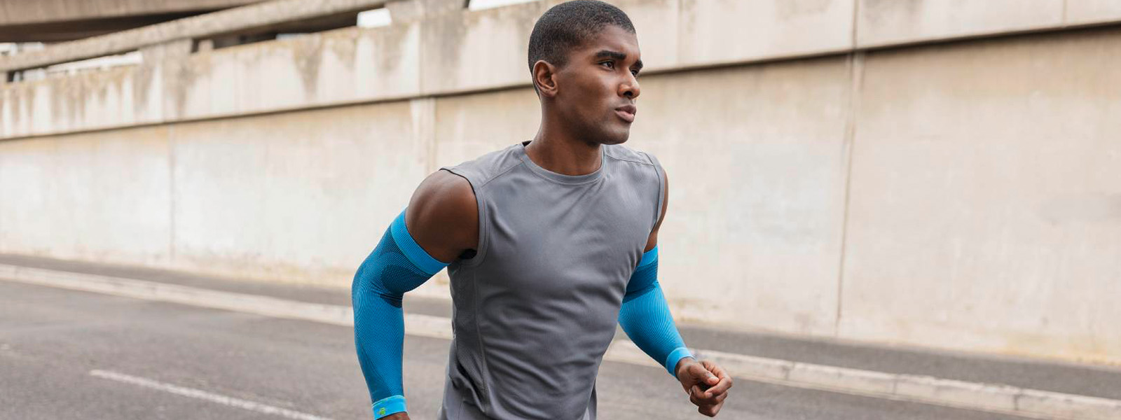 Man jogs in the city and has blue compression arm sleeves