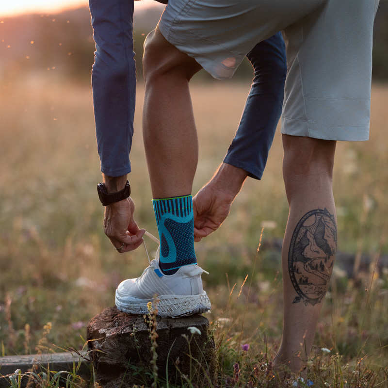 Man with an foot bandage binds running shoe with his foot on a tree stump