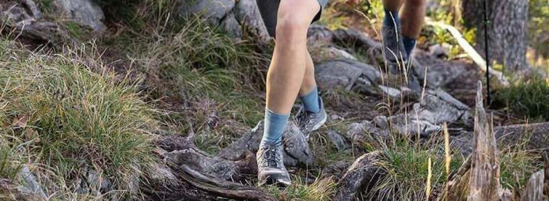 Wandering woman on a stony surface wears medium -length hiking socks