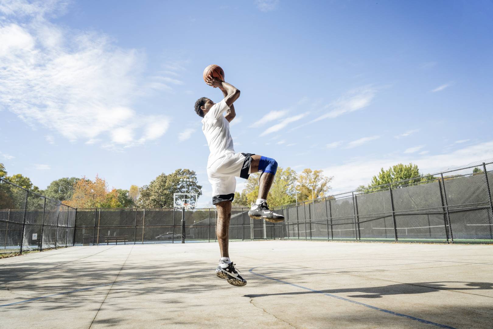 Basketball players jump on a street court for the throw from hands with the ball over the head, bent into the other, show the other vertically downwards