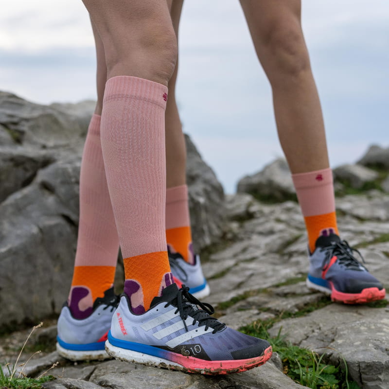 Pink medium -long and compression socks of the Trail Run Sock from Bauerfeind Sports on a rock